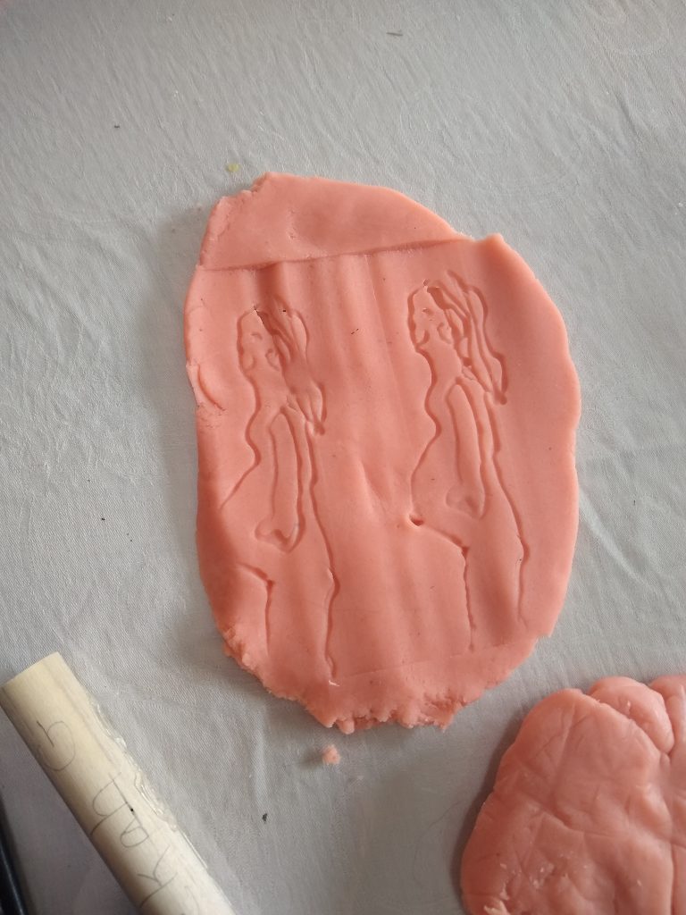 Playdough with the figure of a very pregnant woman stamped onto it